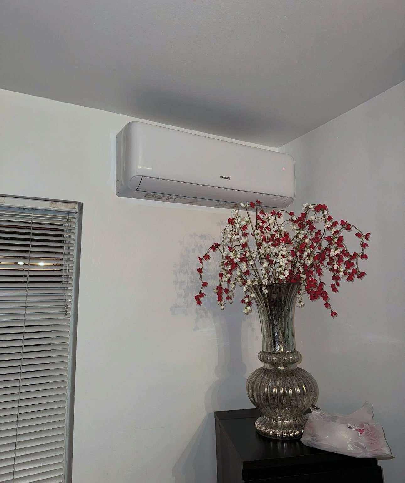 Wall-mounted mini-split indoor unit in room with vase of flowers